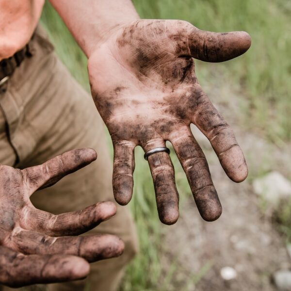 A man with his hands covered with mud