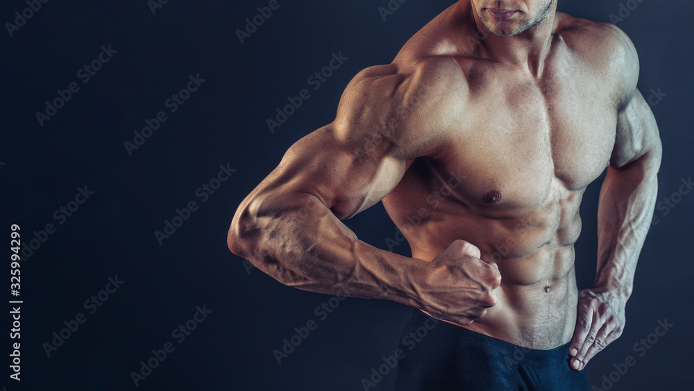 Unrecognizable Strong Athletic Sexy Muscular Man Poising , Showing biceps and delts on Black Background.